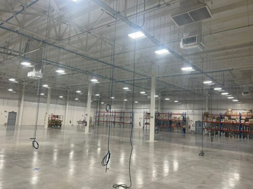 Empty warehouse facility showing large storage space, flooring, and lights.